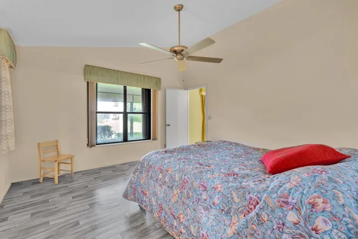 Vaulted ceiling with a ceiling fan, light-toned walls, and wood-finish flooring