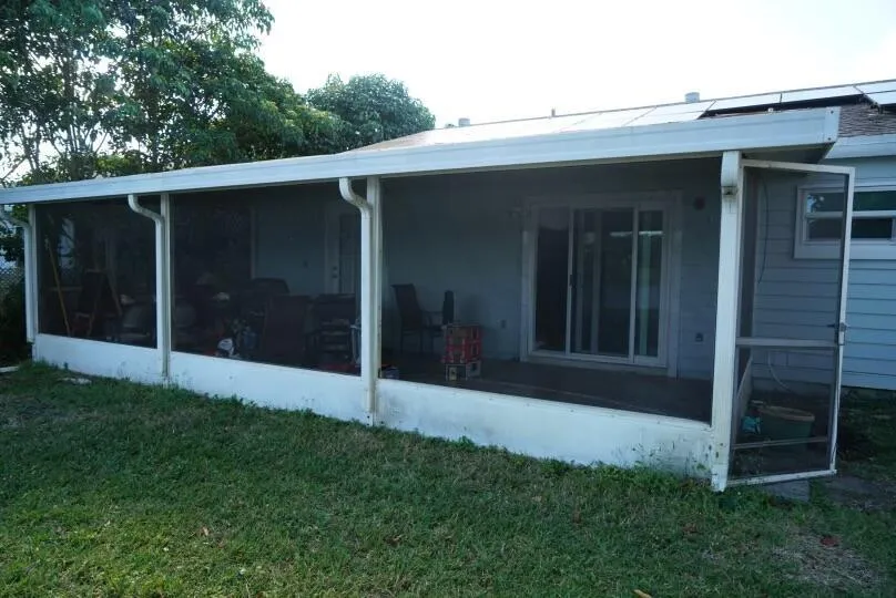 Screened patio with a covered roof, white gutters, and a sliding glass door entry