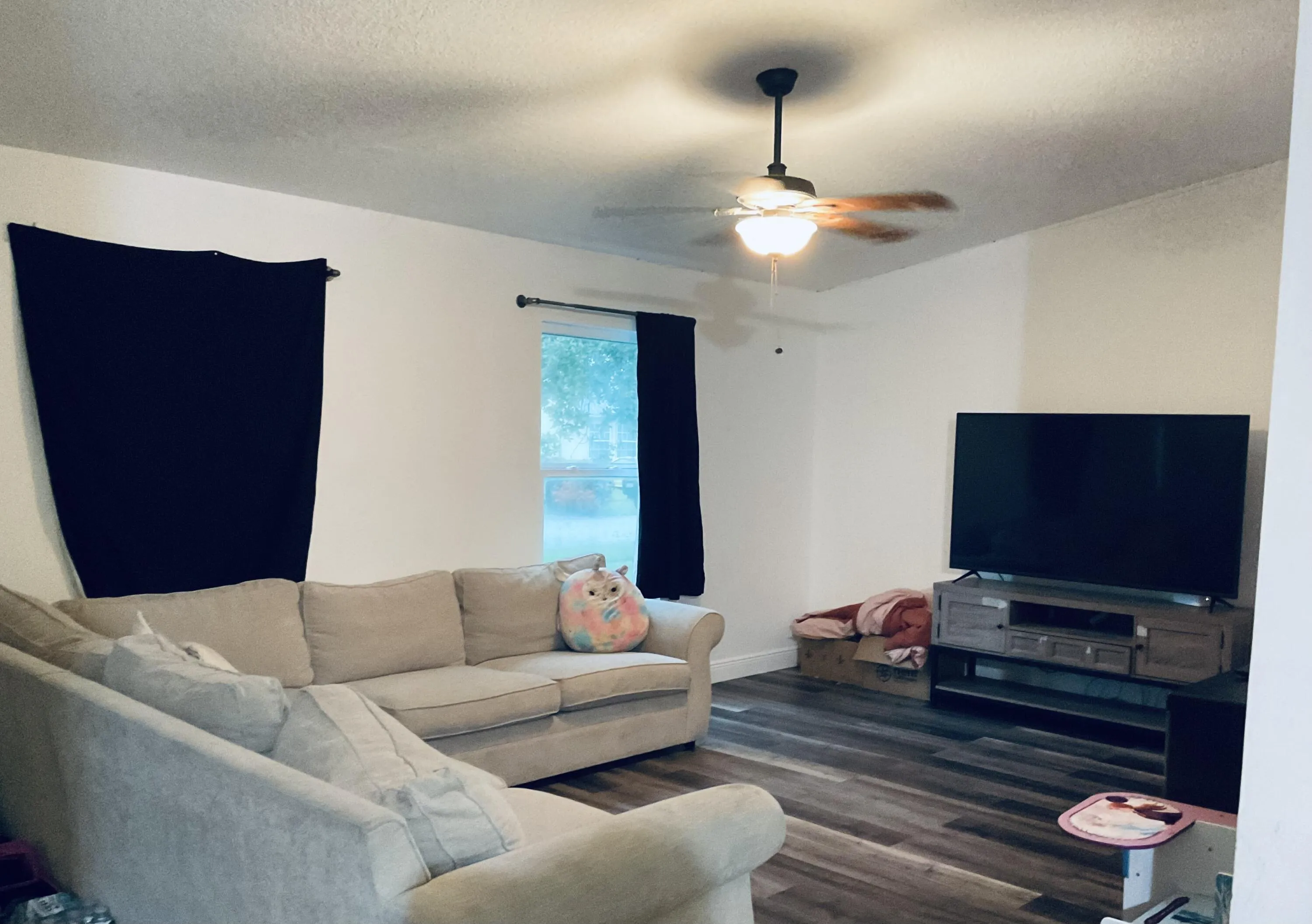Wood-finish flooring, white walls, and a ceiling fan with integrated lighting