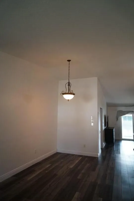 Wood-finish flooring with a semi-flush mount light fixture and a wall partition, could be used as a breakfast/coffee/wine nook