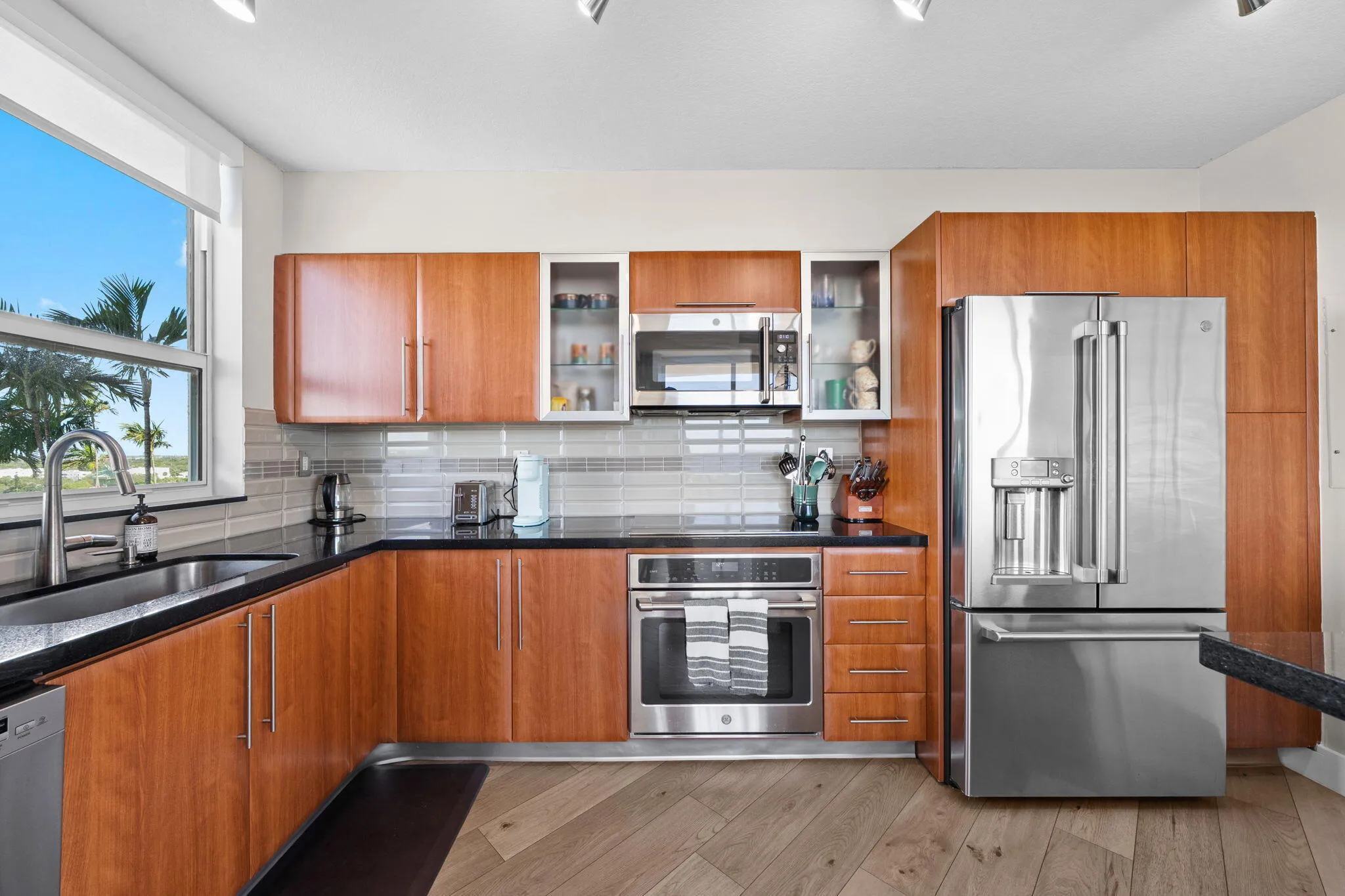 Well-appointed kitchen featuring wood cabinetry, granite countertops, stainless steel appliances & glass tile backsplash.