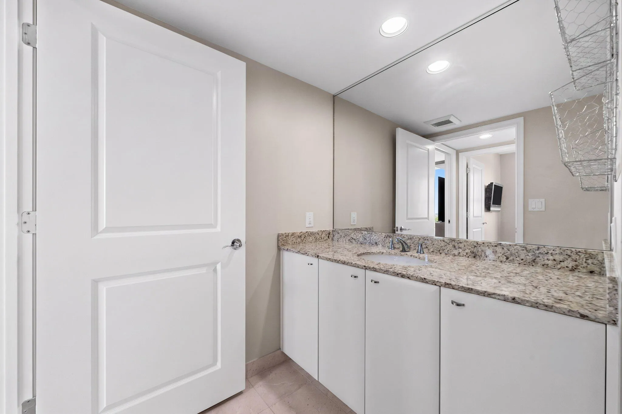 Alternate view of the second full bath highlighting the long granite vanity, generous cabinet storage & oversized mirror.