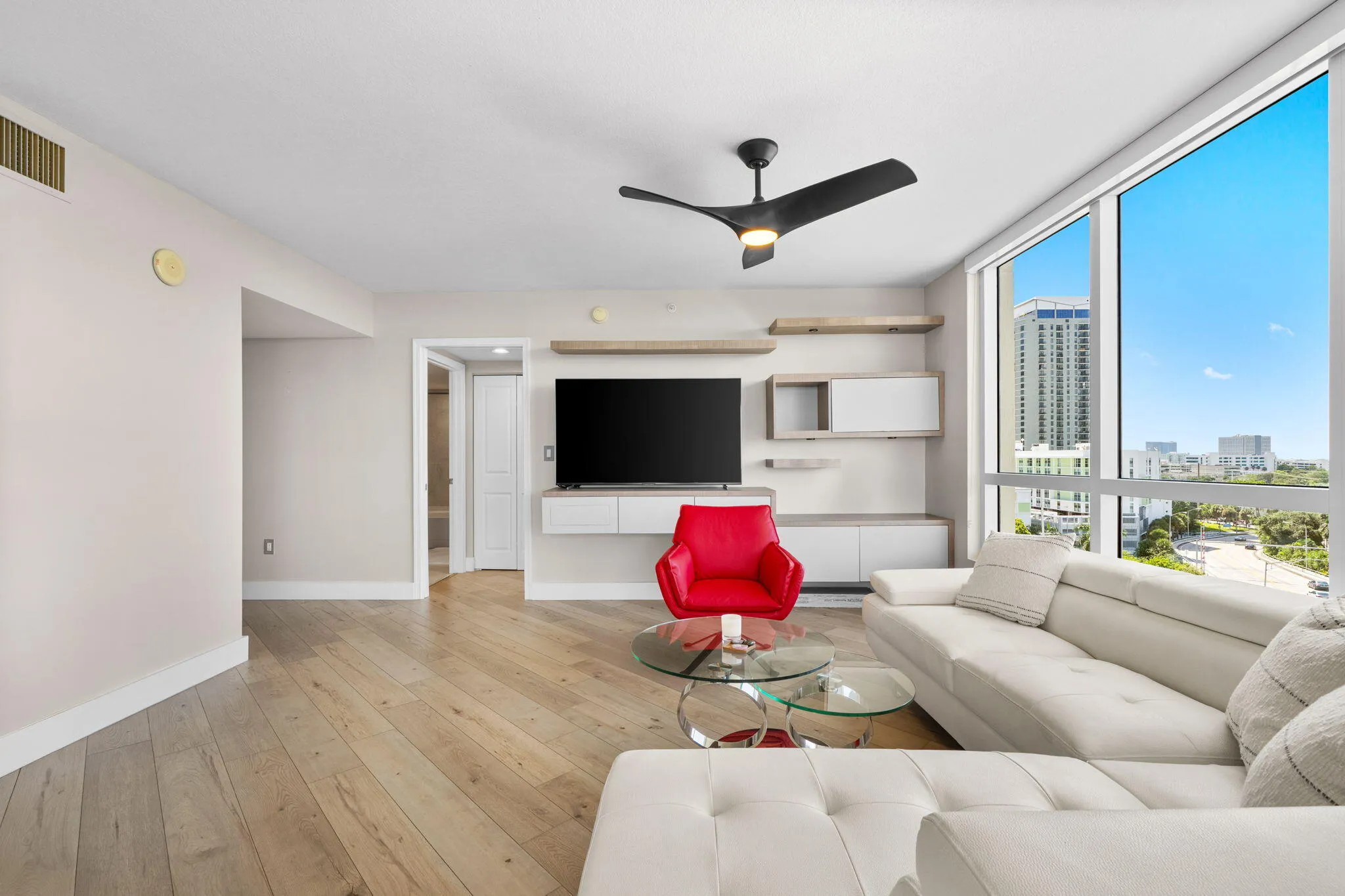Refined living area with wood-look flooring, custom built-in media & display cabinetry, expansive windows & abundant natural light.