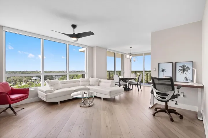 Bright, open living & dining areas feature wood-look flooring, expansive corner windows, modern furnishings & sliding glass doors extending the space to the wraparound terrace.