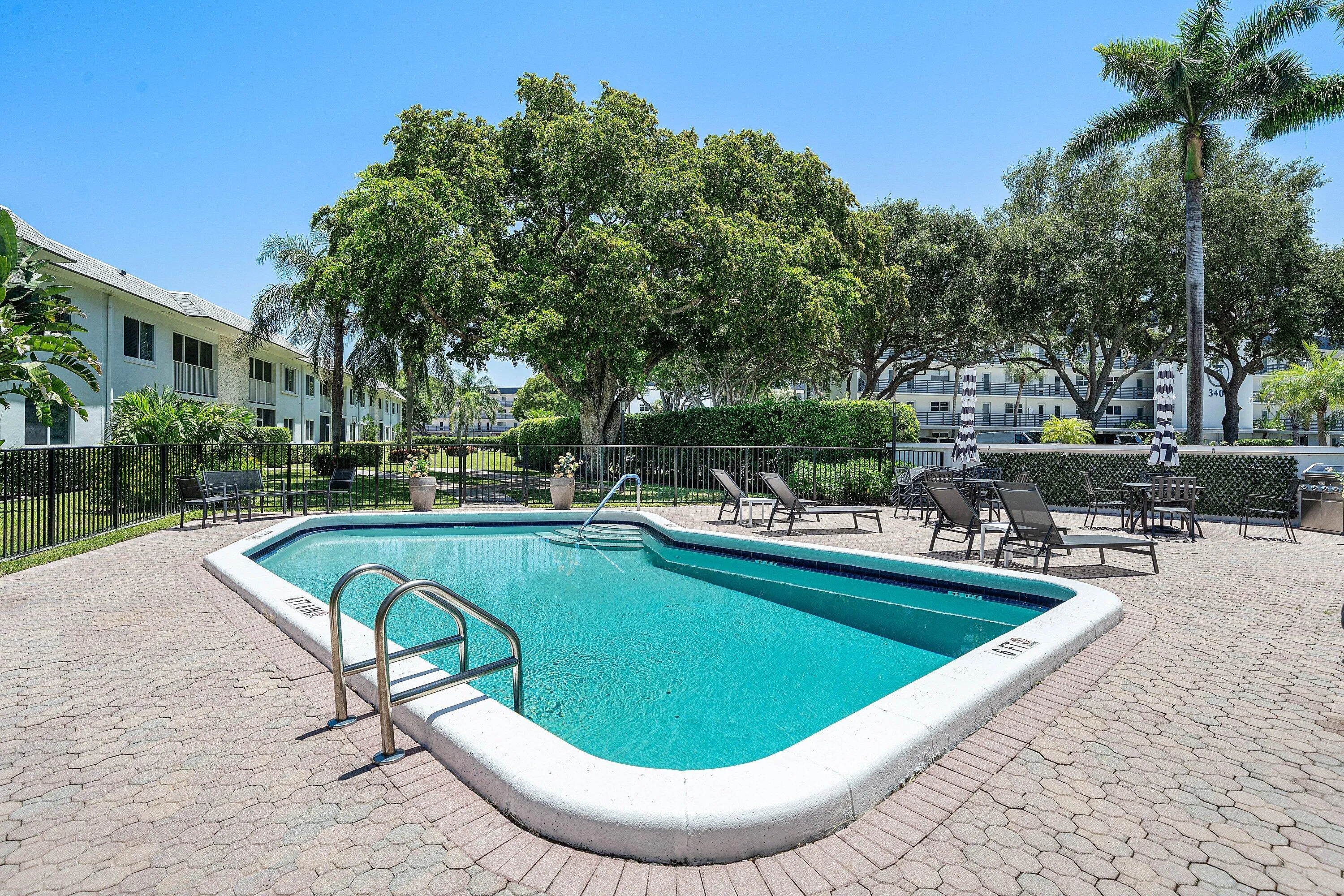 Swimming pool with integrated steps and stainless steel handrails, surrounded by a paver patio