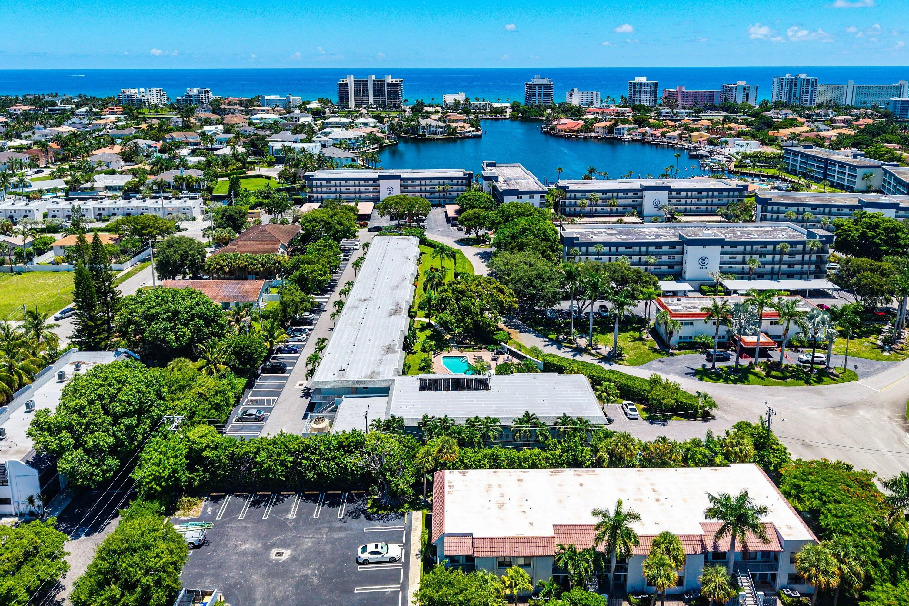 Coastal proximity, expansive water body, lush landscaping, mature palm trees, multi-story structures
