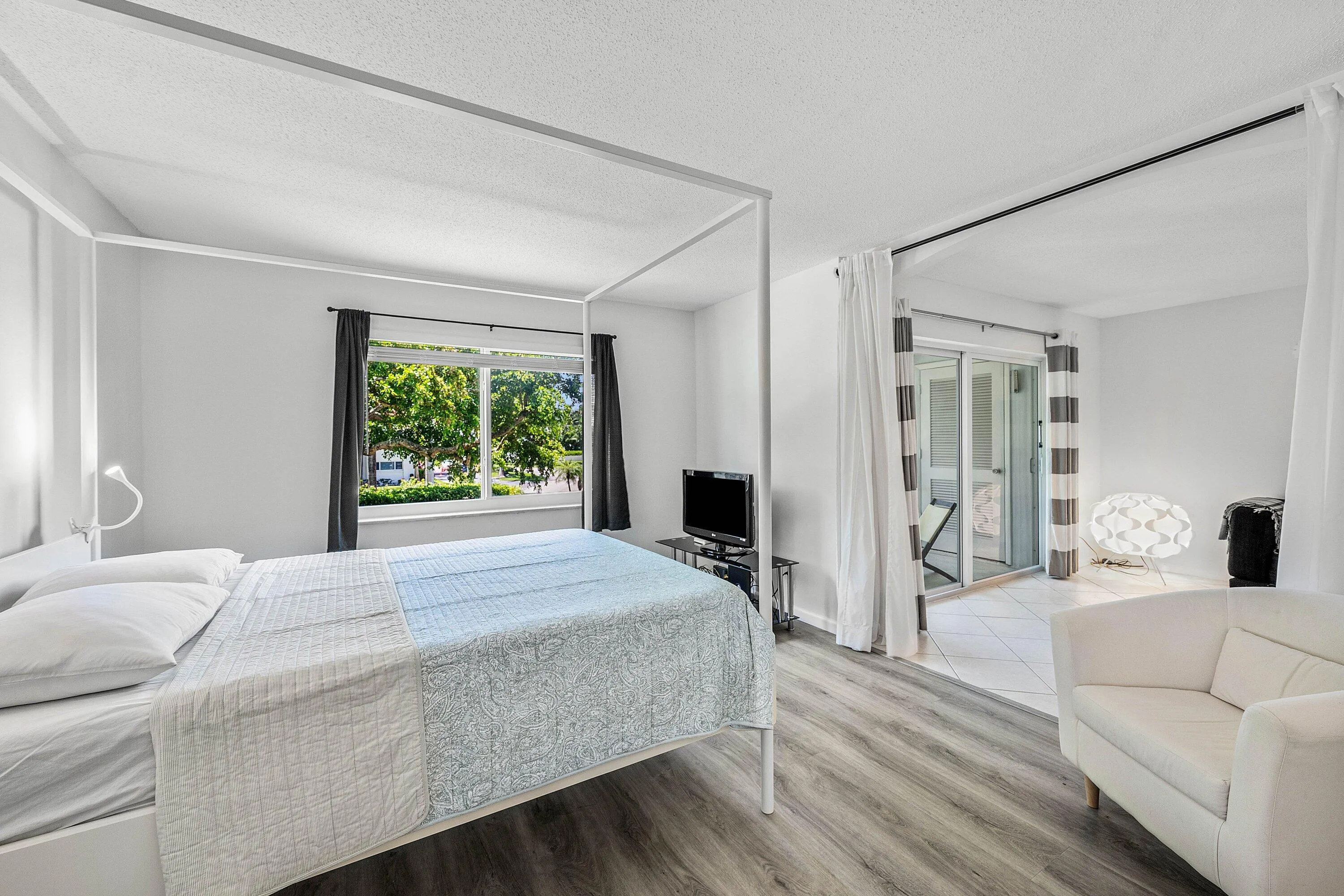 Hardwood-finish flooring, sliding glass door access to a tiled outdoor area, and a large window