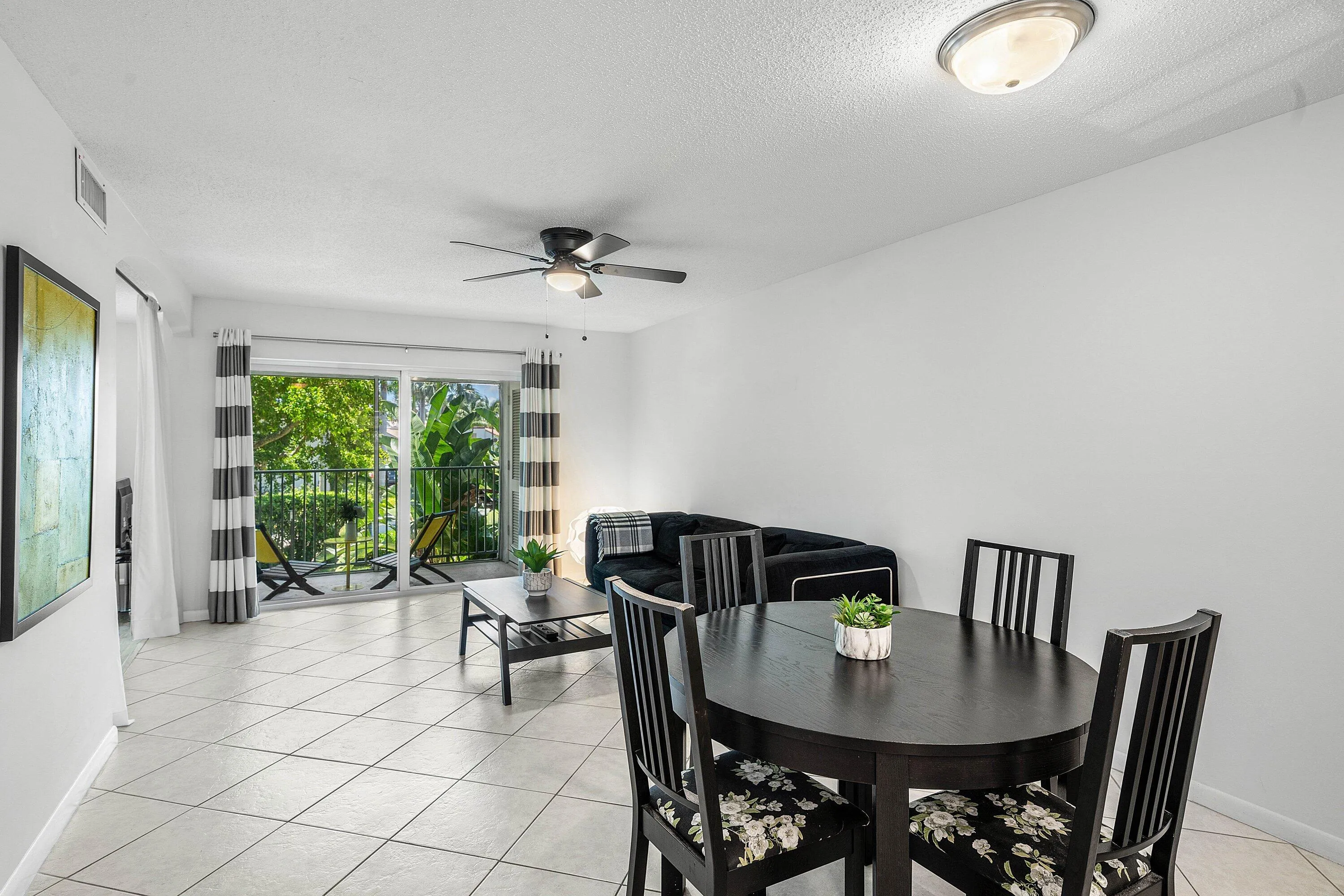 White tile flooring, sliding glass doors to a balcony, a ceiling fan with integrated lighting, and a flush-mount ceiling light fixture