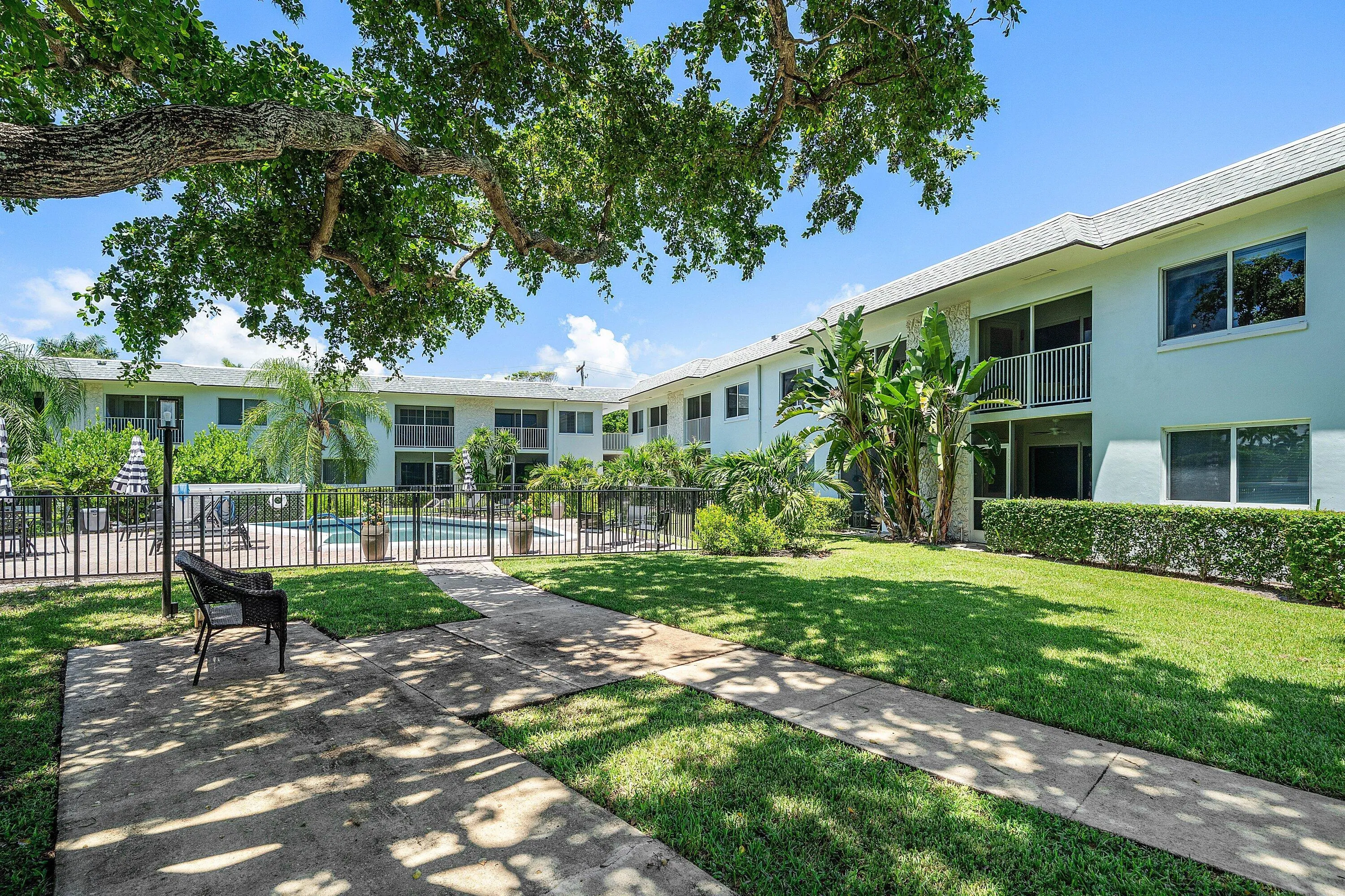 Expansive green lawn with mature trees and paved pathways