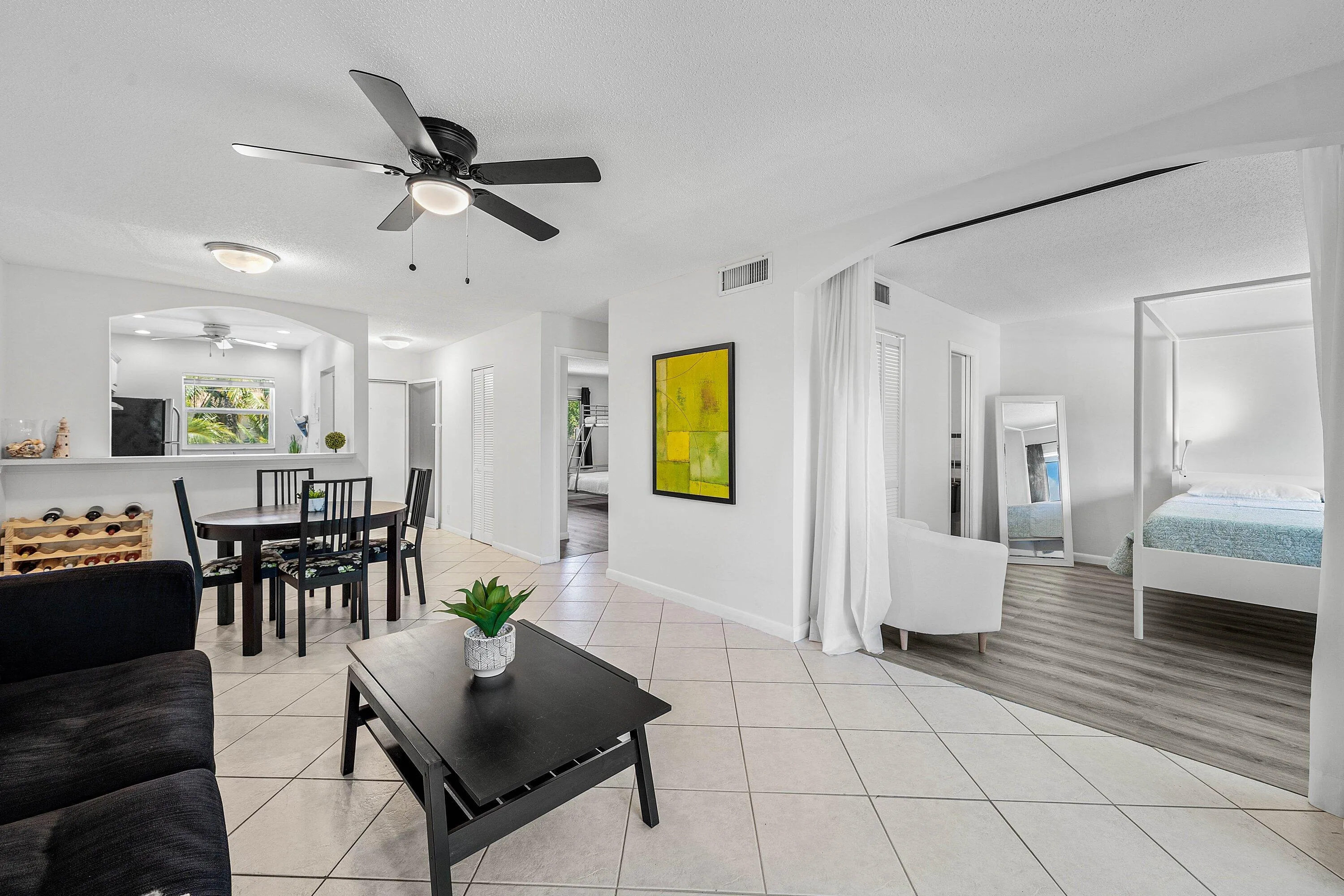 Open-concept living area with tiled flooring, a dining space, and an arched pass-through window to the kitchen