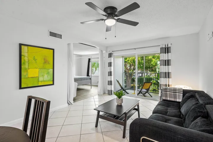 Tiled flooring throughout, ceiling fan with integrated lighting, and a sliding glass door to a private balcony
