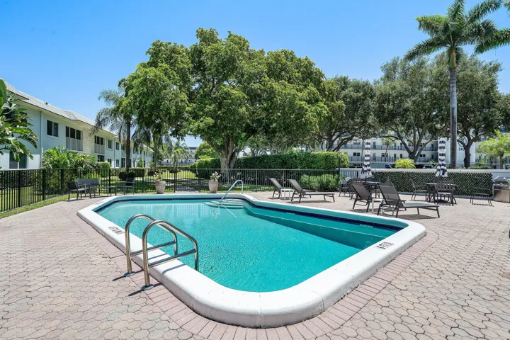 Swimming pool with integrated steps and stainless steel handrails, surrounded by a paver patio