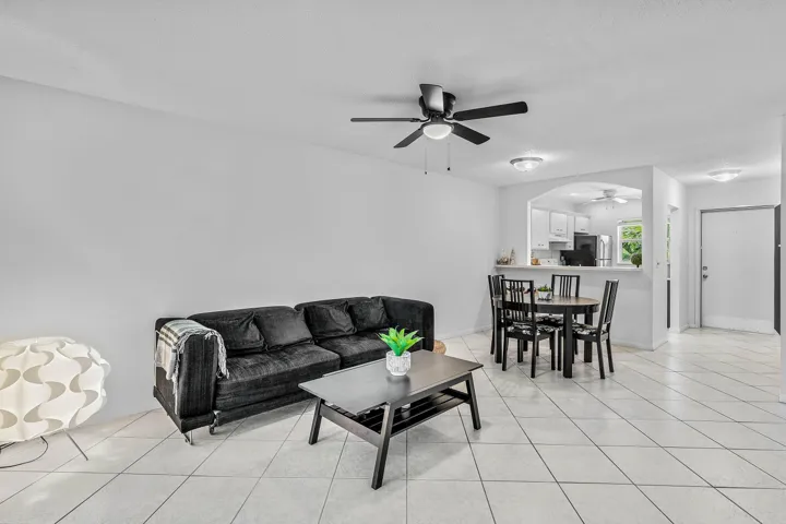 Open-concept living area featuring tile flooring, ceiling fan with integrated lighting, and an arched pass-through to the kitchen