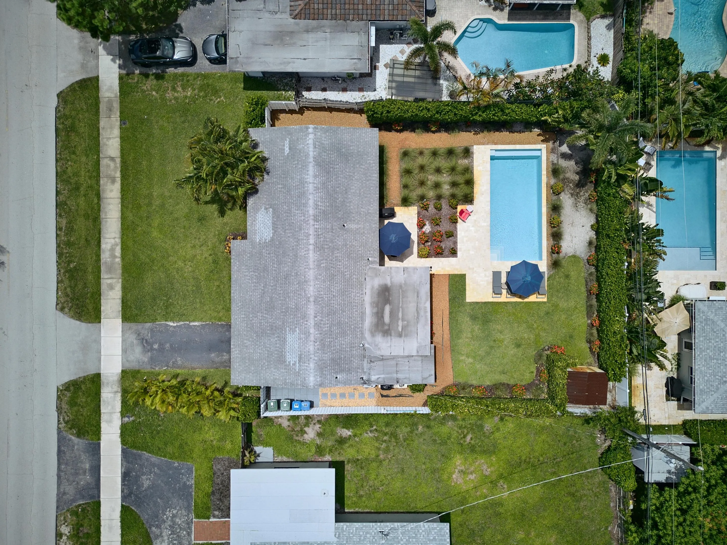 Rectangular swimming pool with light-colored decking, surrounded by mature landscaping and a well-maintained lawn
