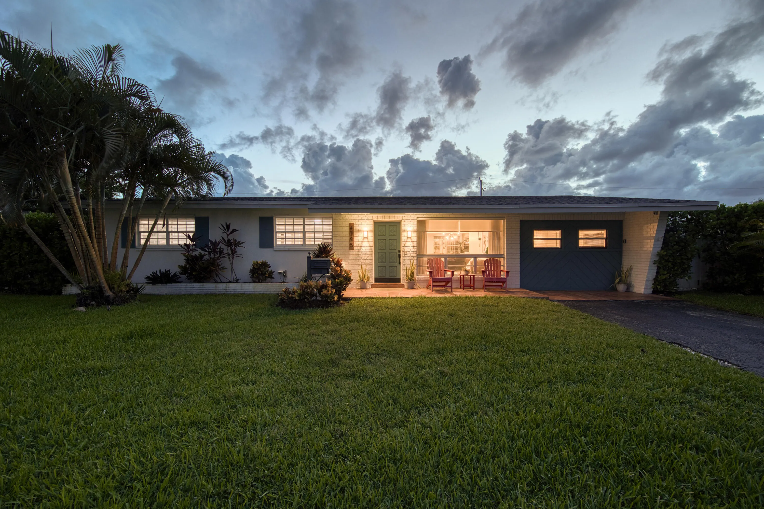 Modern single-story residence featuring a clean-lined facade with extensive glazing, illuminated interior spaces, and a recessed entry