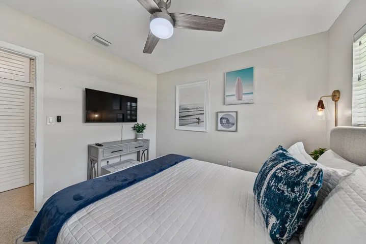 Ceiling-mounted fan, wall-mounted television, built-in wall sconce, and louvered bifold door