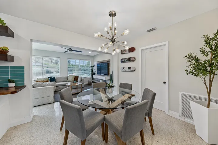 Open-concept living space featuring a modern sputnik chandelier, wood-finish shelving, and a teal subway tile backsplash