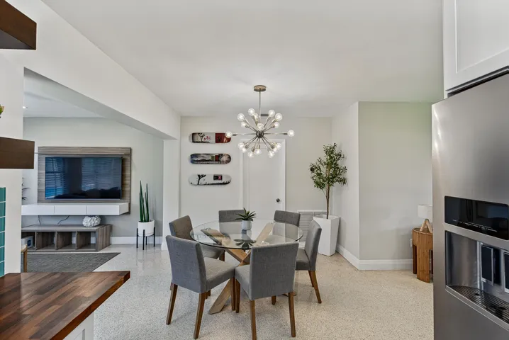Open-concept living space featuring a modern Sputnik-style chandelier, a glass-top dining table, and light-toned terrazzo flooring