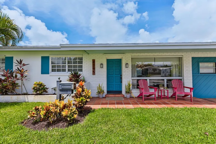 Charming single-story home featuring a fresh white and cream exterior with contrasting teal blue accents and shutters