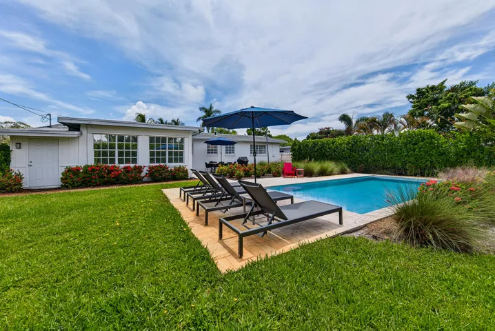 Rectangular swimming pool with a surrounding paver patio, lush green lawn