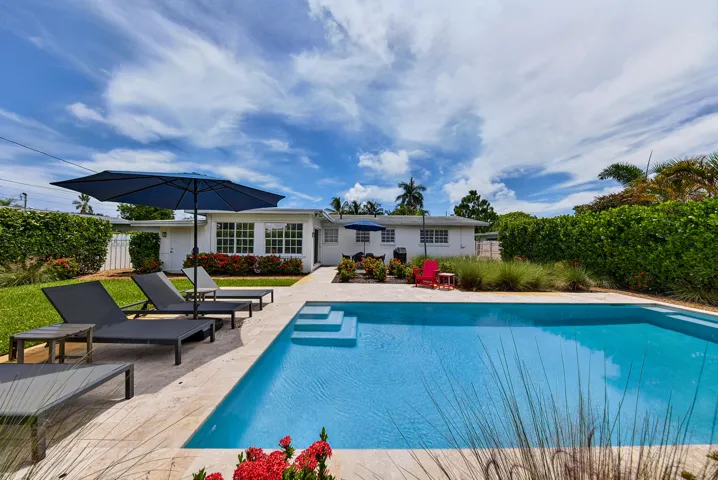 Outdoor swimming pool with integrated steps, surrounded by stone-look patio pavers, manicured lawn