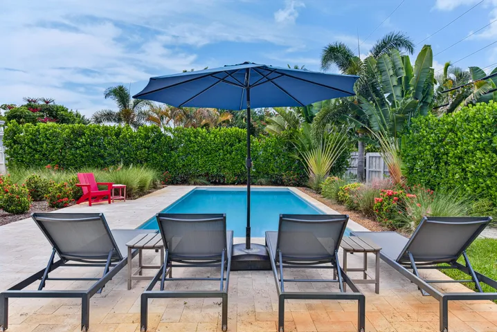 Private backyard featuring a swimming pool, extensive landscaping, and a paver deck