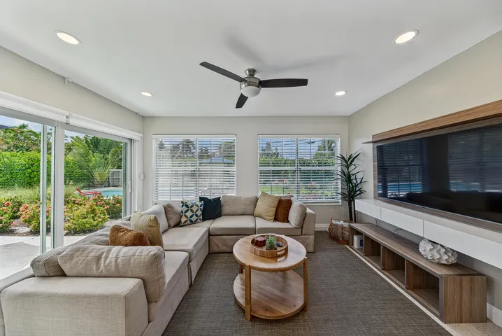 Recessed lighting, ceiling fan, impact sliding glass doors, multiple windows with blinds, and a built-in media console