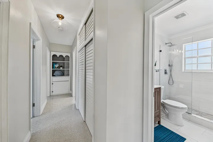 Hallway with built-in shelving, louvered closet doors, and recessed lighting