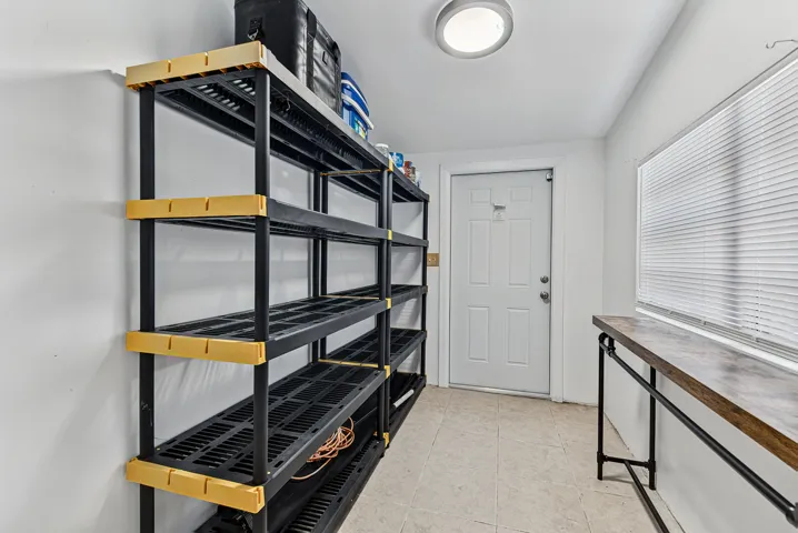 Storage area featuring built-in shelving, a panel door, a large window, a light fixture