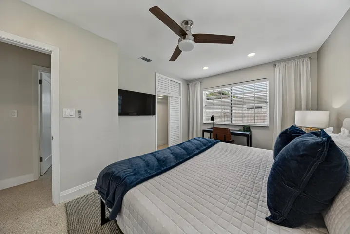 Recessed lighting, ceiling fan, window with blinds and drapes, and built-in closet with louvered doors