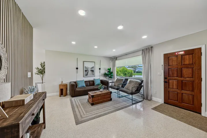 Recessed lighting and a paneled accent wall complement the light-colored flooring