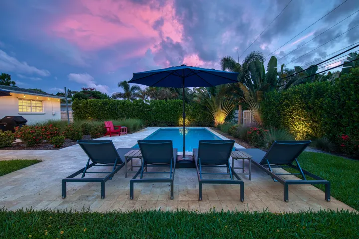 Rectangular swimming pool surrounded by a paver patio and lush landscaping
