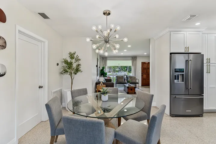 Open concept dining area with a contemporary sputnik chandelier, light-toned flooring, and white wall finishes