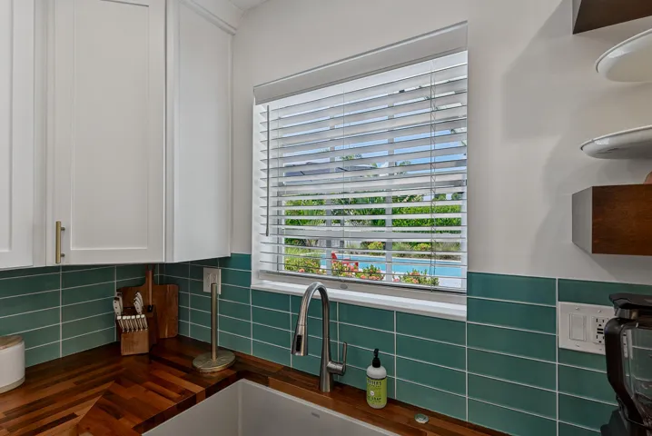 White shaker-style cabinetry with gold-finish hardware, wood-finish countertops, and a subway tile backsplash