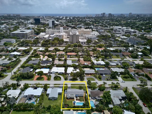 Aerial view showcasing an expansive lot with mature landscaping, resort-style swimming pool, and manicured grounds