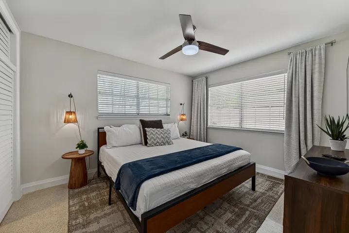 Dual windows with blinds, ceiling fan with integrated lighting, and white louvered closet doors