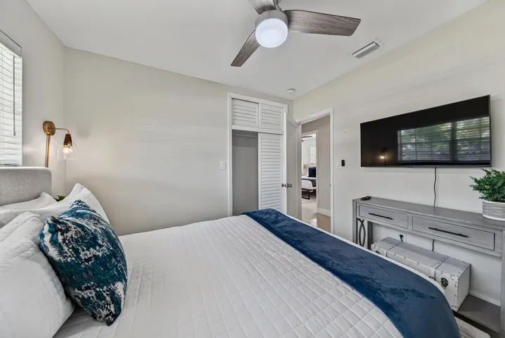 Integrated ceiling fan, louvered bi-fold closet doors, wall-mounted light fixture, window with blinds