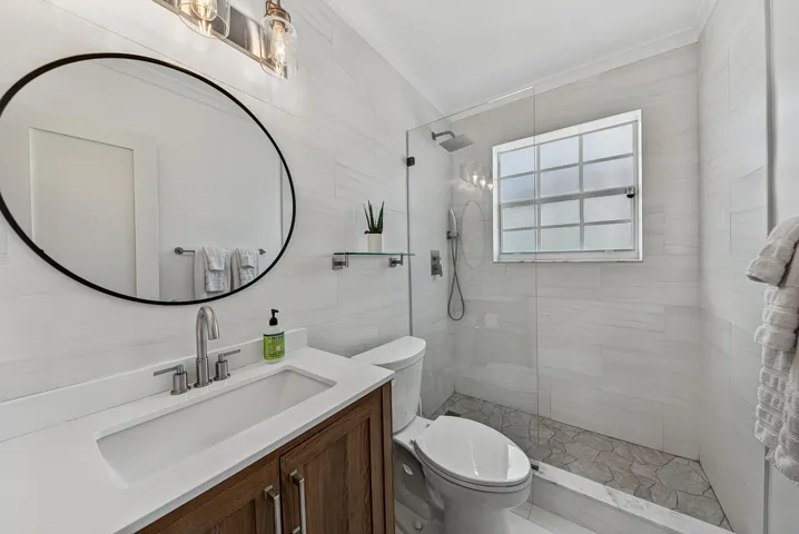 Floating vanity with wood-finish cabinetry, white countertop, and integrated rectangular sink