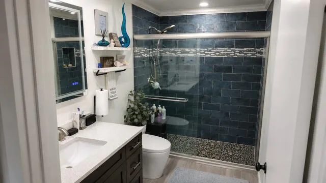 This beautiful renovated primary bathroom features a striking walk-in shower with rich color tile work, pebble- stone flooring, smart toilet with heated seat, and sleek modern finishes.
