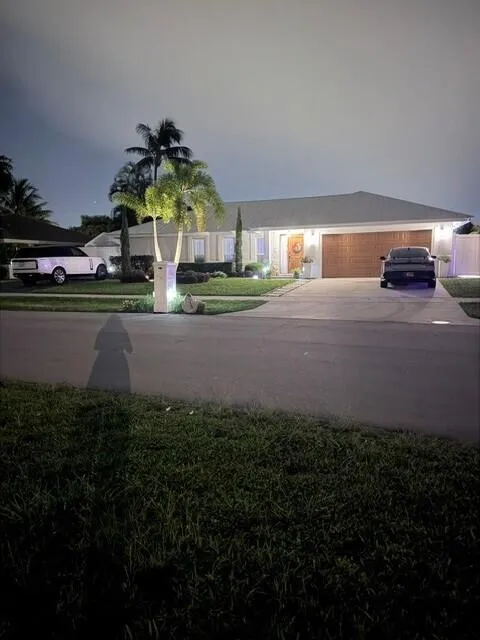 Beautifully illuminated at night, this inviting home showcases exceptional curb appeal with lush topical landscaping and a war, welcoming entrance. Elegant exterior lighting highlights the home's architecture and creates a striking first impression after sunset.