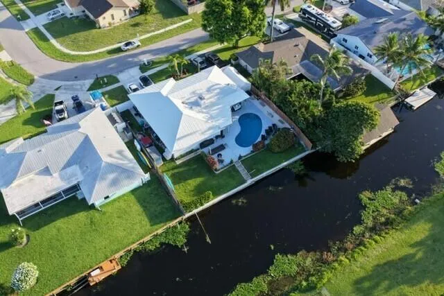 This stunning aerial view showcases the home's prime waterfront setting within a peaceful canal-front neighborhood. The private pool, lush landscaping, and expansive canal views capture the essence of relaxed South Florida living.