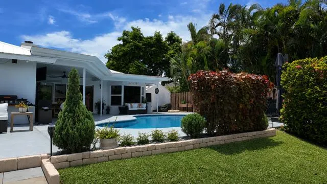 From the canal, this beautifully landscaped backyard showcases a sparkling pool framed by custom stone walls and lush tropical greenaery. The inviting outdoor living area creates a private setting perfect for entertaining.