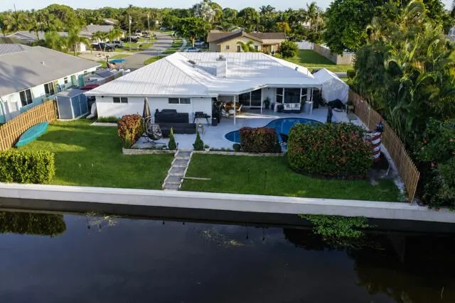 A stunning aerial view showcases this waterfront property with a spacious backyard, private pool, covered patio, and direct frontage along the navigable canal. Its beautiful landscaped with a concrete seawall completing this waterfront retreat!