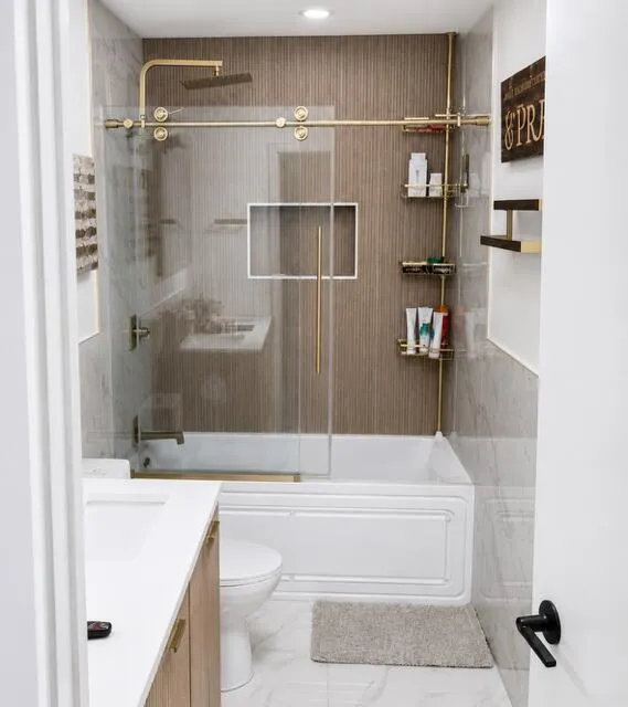 Beautifully remodeled bathroom featuring warm neutral relaxing tones, double sinks, a luxurious Jacuzzi style tub, and a sleek glass enclosed shower.