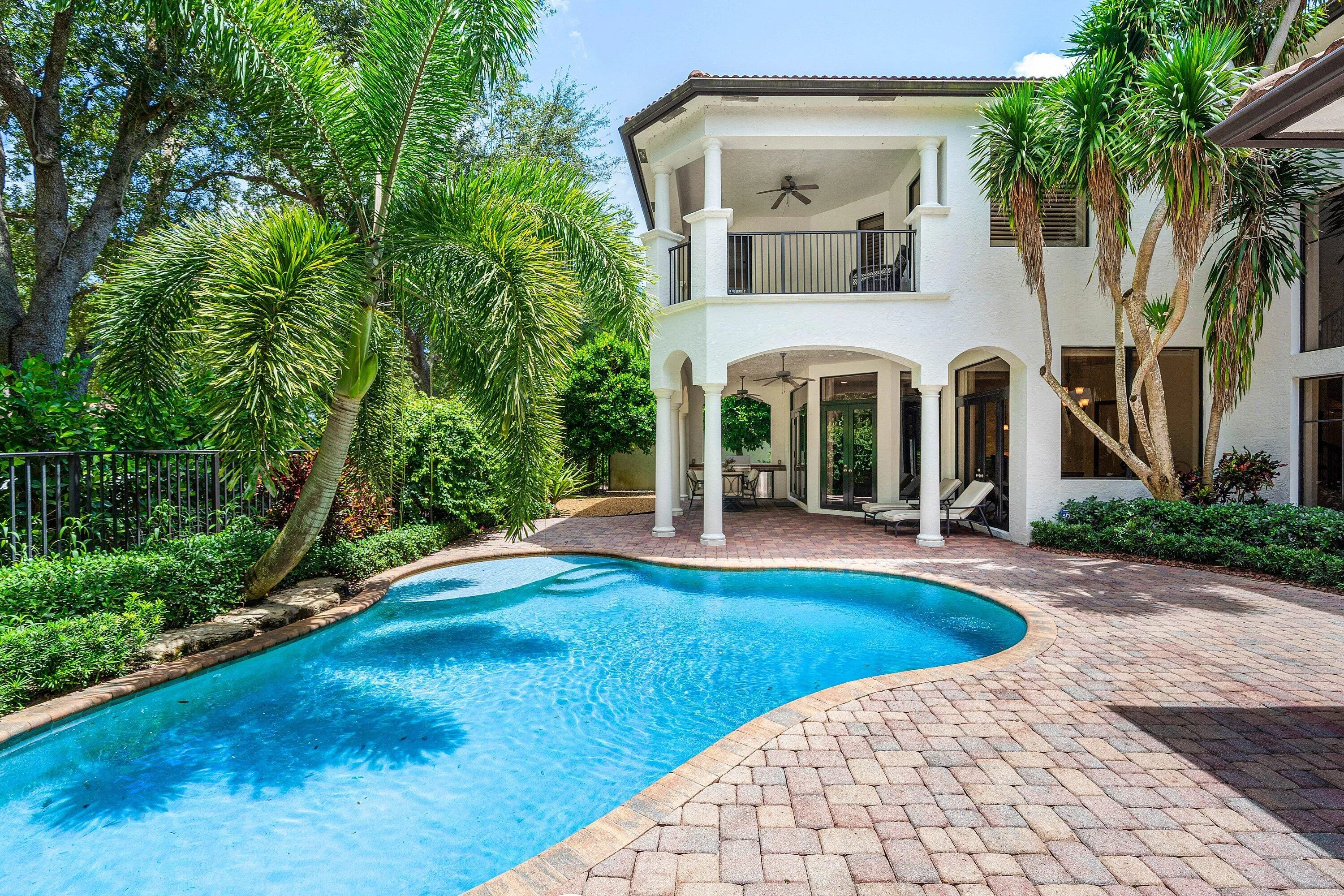 Primary Suite features a private covered balcony overlooking the pool and lush backyard