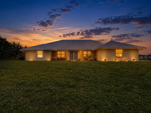 Single-story residence featuring a metal roof, stucco exterior, and front yard landscaping