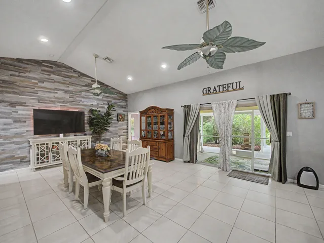 Vaulted ceiling with recessed lighting, tile flooring, accent wall with horizontal paneling, and sliding glass doors
