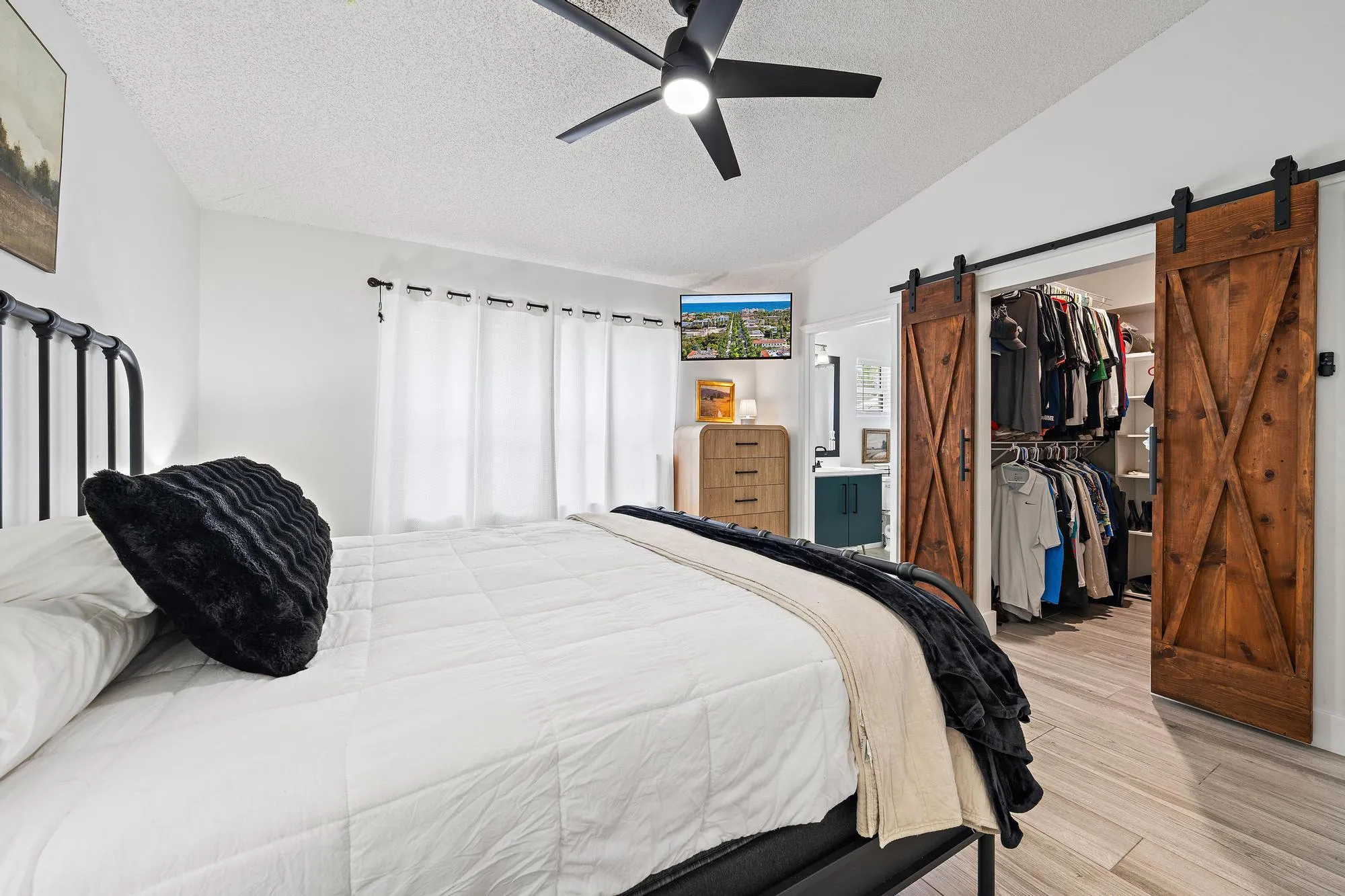Black ceiling fan, light wood-finish flooring, sliding barn doors, organized closet, and recessed lighting