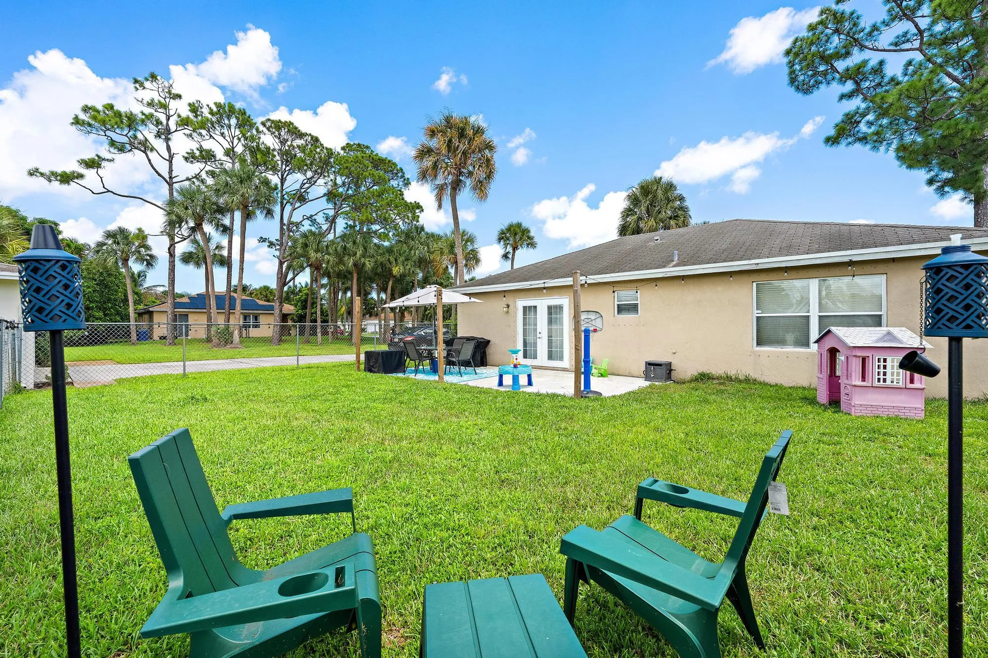 Expansive backyard featuring a manicured lawn, established palm trees, and a concrete patio