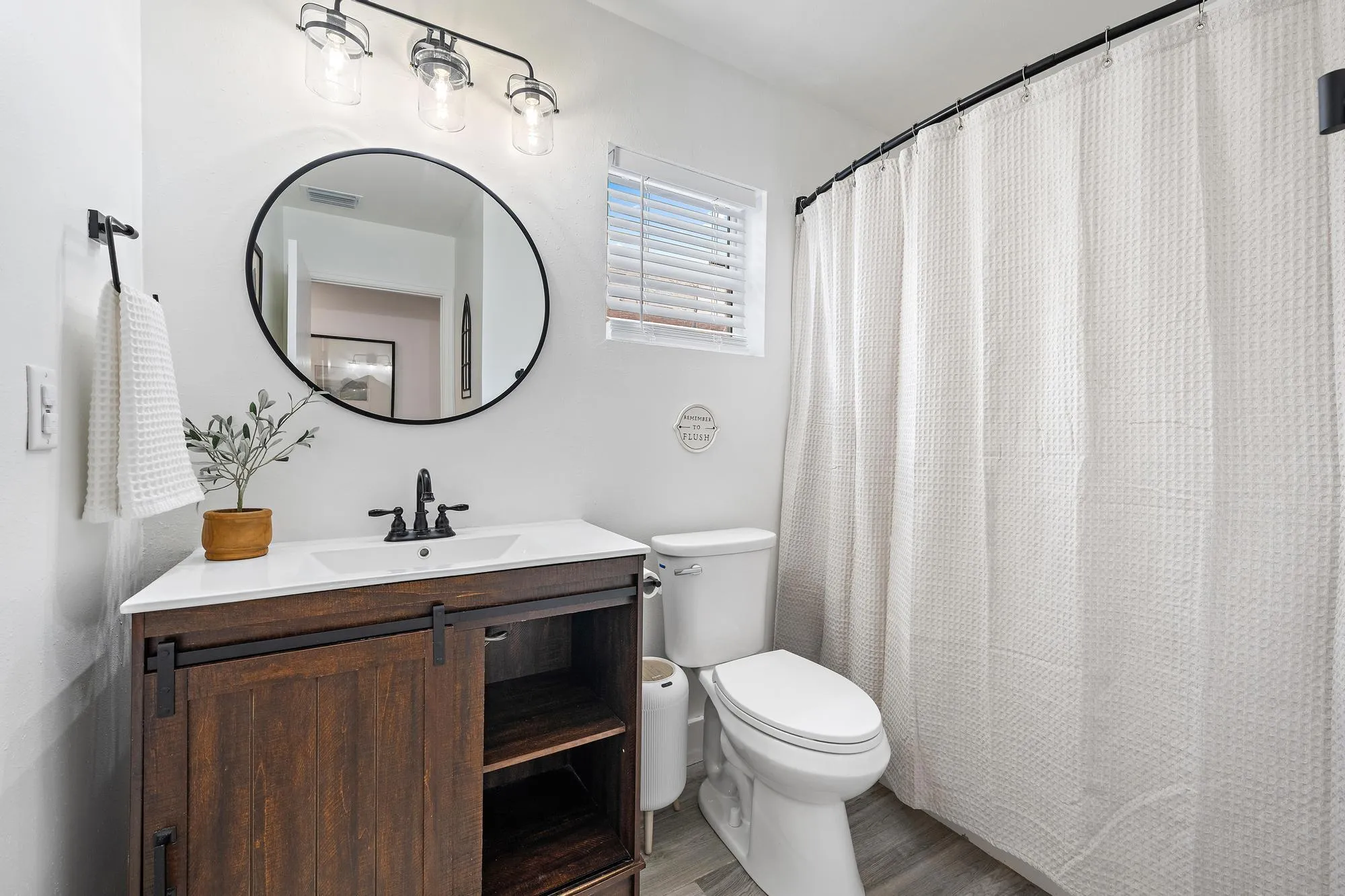 Wood-finish vanity with a sliding barn door, white countertop, and matte black faucet